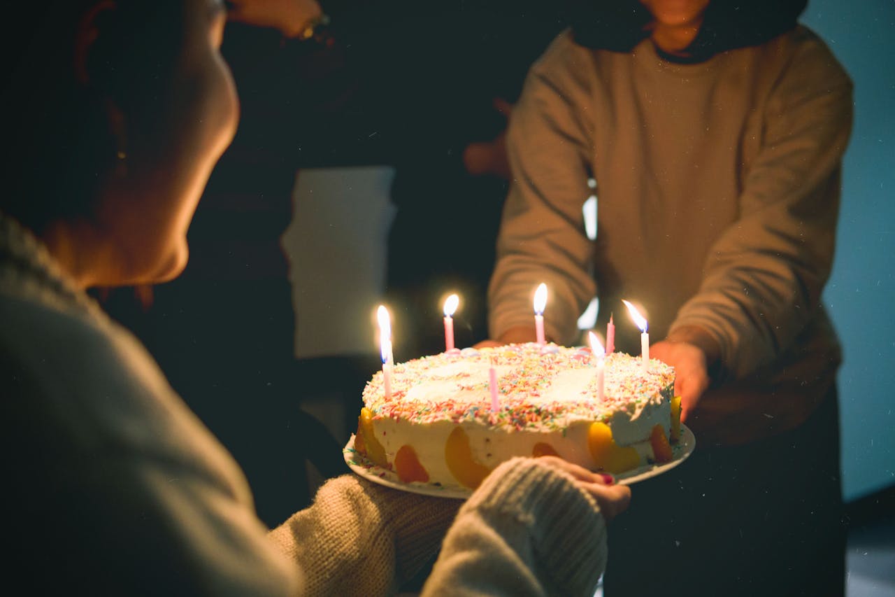 Warm and festive birthday scene featuring a colorful cake with lit candles, captured indoors.